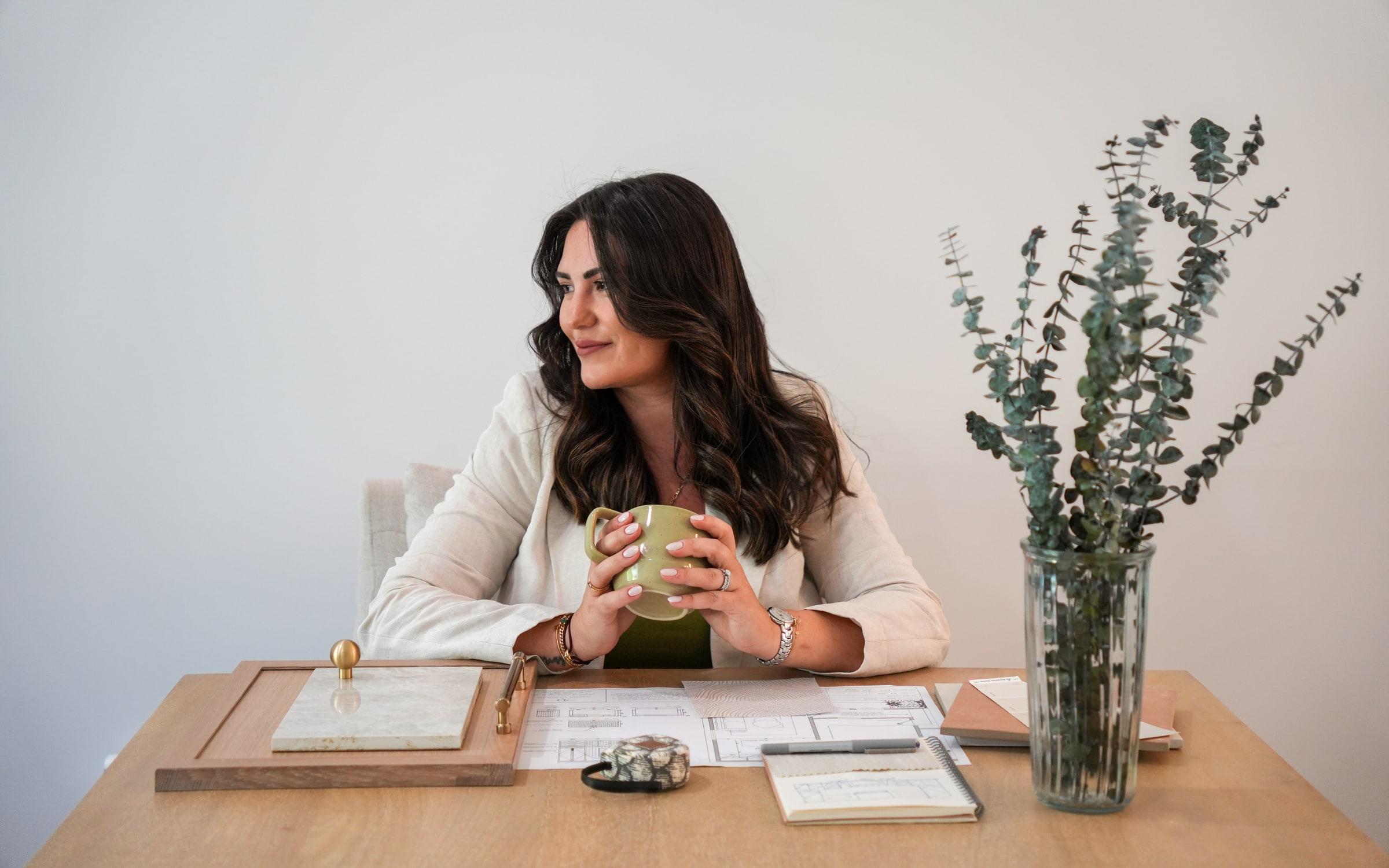 Nadine Donohoe at her studio desk with drawings, material samples and eucalyptus.